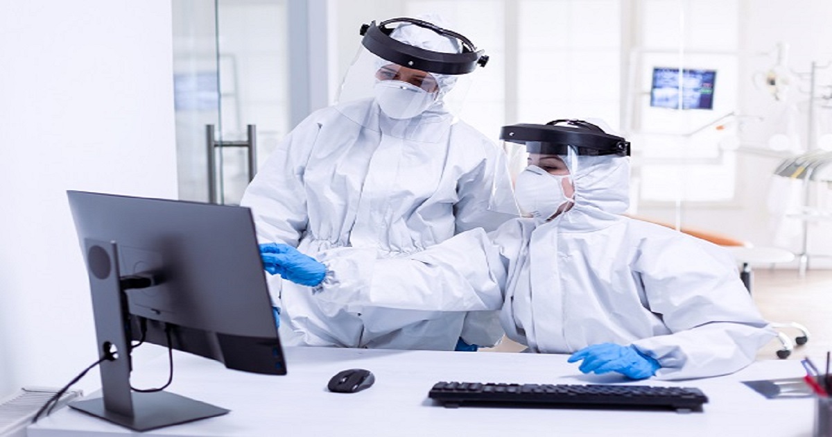 doctor nurse ppe suit looking monitor during global pandemic with covid 19 medicine team wearing protection gear against coronavirus pandemic dental reception as safety precaution 1